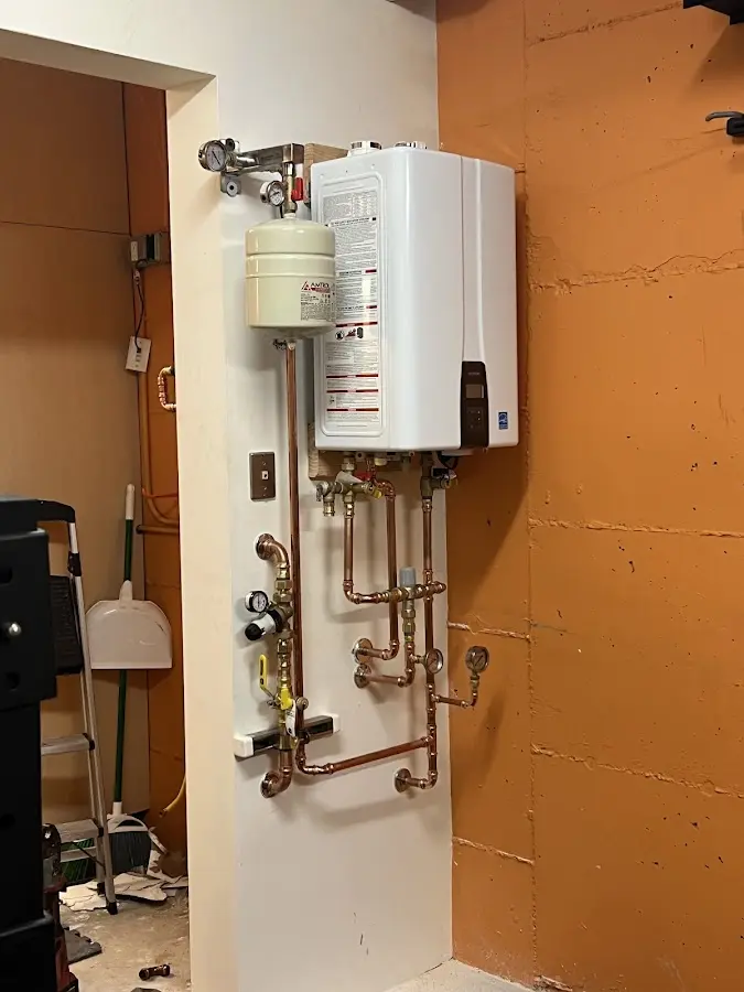 Plumbing technician inspecting water heater connections in Wilmer